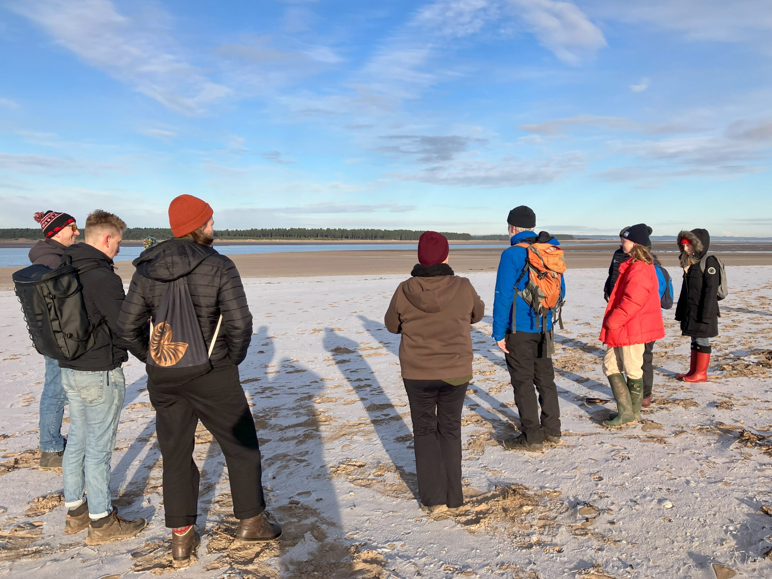 group standing on frosted sand, looking out to the estuary
